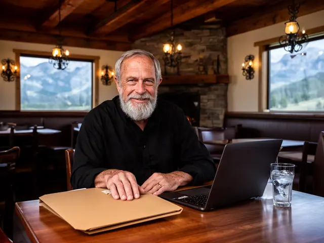 A smiling grey-bearded man with a kraft folder and laptop in a timber-beamed steakhouse.